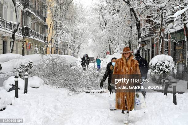 Woman wearing a fur coat walks amid a heavy snowfall in Madrid on January 9, 2021. - Snowstorms across much of Spain left three people dead and...