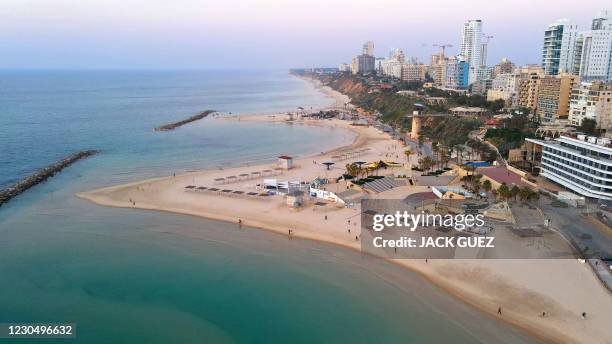 People walk on the beach just before sunset in the Israeli Mediterranean coastal city of Netanya, north of Tel Aviv, on January 9 during an...