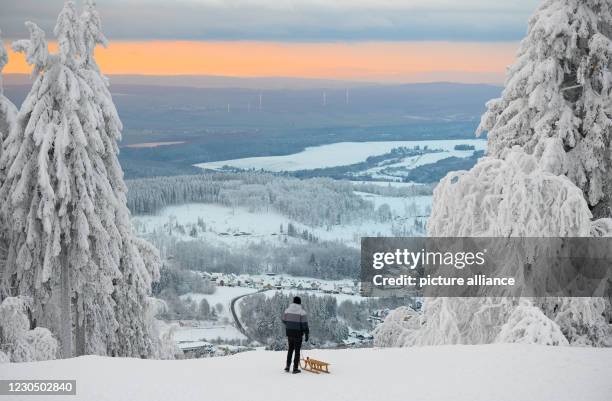January 2021, Hessen, Schmitten: A man looks from the Feldberg summit into the Hintertaunus. The Feldberg area in the Taunus is closed due to snow...