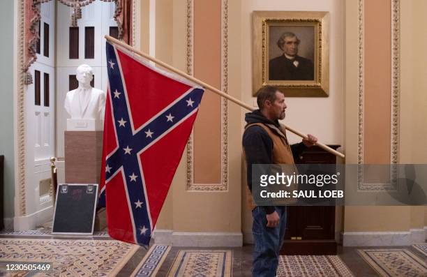 Supporter of US President Donald Trump holds a Confederate flag outside the Senate Chamber during a protest after breaching the US Capitol in...