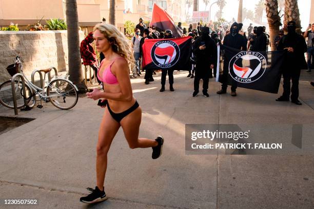 Pedestrian jogs past counter-protesters, some carrying ANTIFA flags, as they wait to confront a "Patriot March" demonstration in support of US...