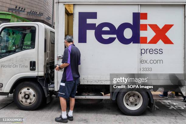 FedEx Express courier prepares numerous packages inside the delivery truck parked on the street.