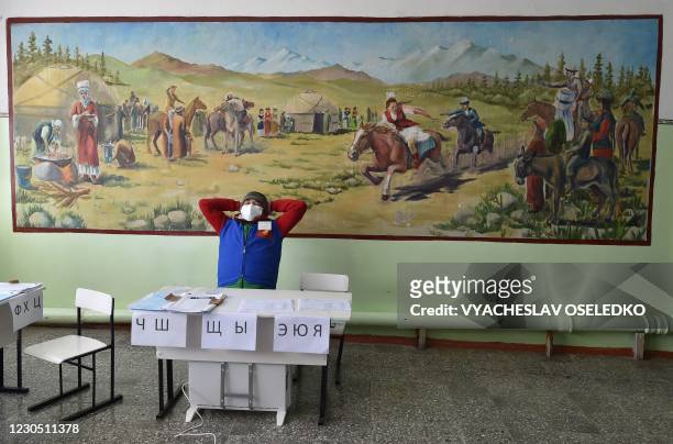 Member of a local electoral commission stretches at a polling station during Kyrgyzstan's presidential election and a referendum on government system...