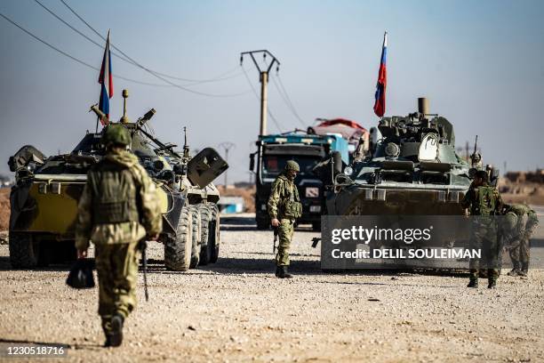 Russian troops escort a convoy of Syrian civilians leaving the town of Tal Tamr in the northeastern Hasakeh province, as they return to their homes...