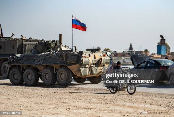 Russian troops accompany a convoy of Syrian civilians leaving the town of Tal Tamr in the northeastern Hasakeh province, to return to their homes in...