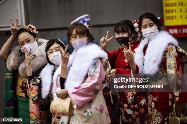 Twenty-year-old women dressed in kimonos flash victory sign outside Todoroki Arena during the "Coming-of-Age Day" celebration ceremony in Kawasaki,...