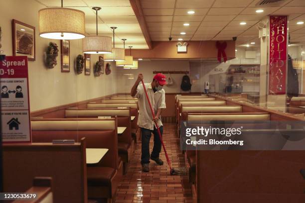 Worker wearing a protective mask mops the floor of the inside dining area of a restaurant in New York, U.S., on Wednesday, Dec. 16, 2020. A major...