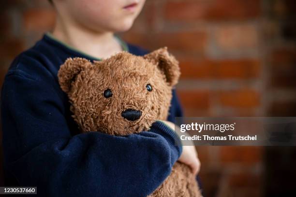 Symbolic photo on the subject of psychological stress on children in the lockdown during the Corona pandemic. A little boy cuddles with his stuffed...