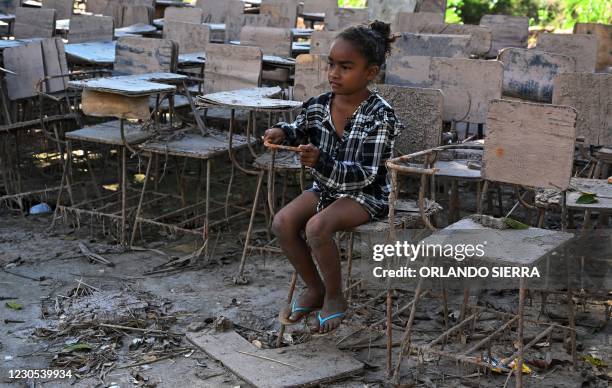 Girl sits on a school chair destroyed during hurricanes Eta and Iota in 2020, in the municipality of La Lima, Cortes Department, Honduras, on January...