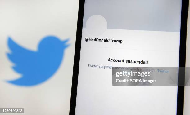 In this photo illustration, an 'Account suspended' message seen on a mobile phone screen in front of the Twitter logo. Twitter permanently suspended...