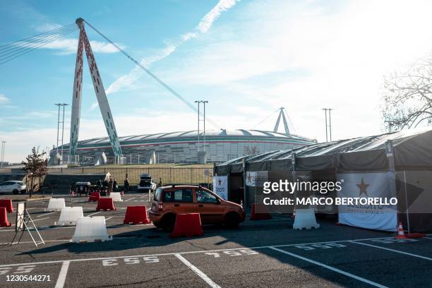 General view shows on January 12, 2021 a car lining up to go through a drive-in swab testing centre for COVID-19 set up by the Italian Army on the...