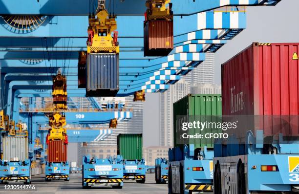 Automated guided vehicles carry containers to and from an automated terminal at Qingdao Port, a free trade zone in Qingdao, east China's Shandong...