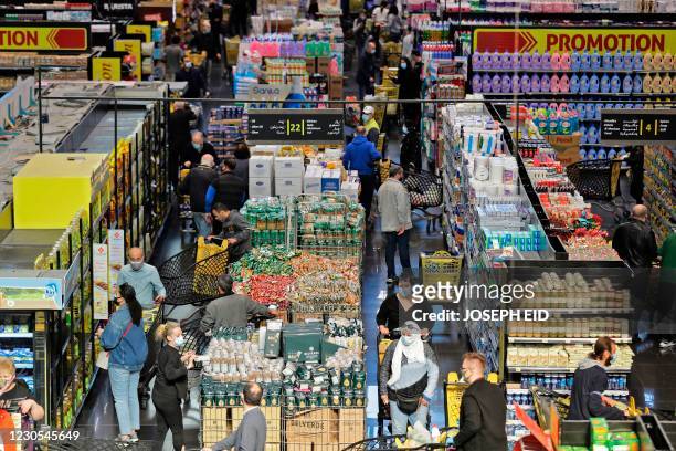 People shop at a supermarket in Beirut as they stock up on provisions two days before a total lockdown due to the spread of the COVID-19 pandemic on...
