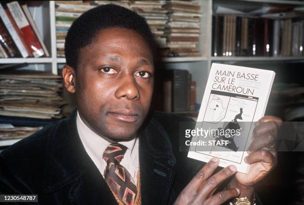 Mongo Beti, écrivain franco-camerounais né sous le nom d'Alexandre Biyidi Awala, pose le 25 février 1976, avec son livre "Main basse sur le Cameroun,...