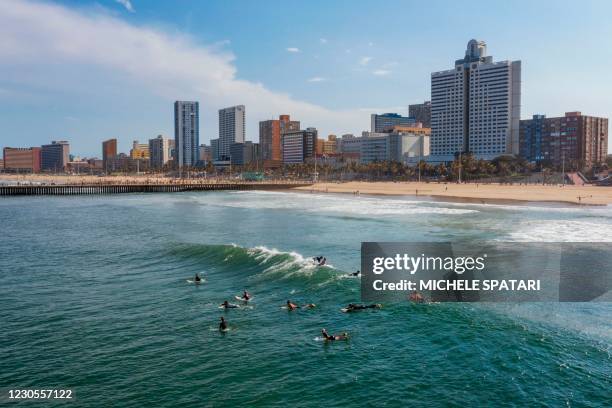 An aerial view shows surfers lining up to ride a wave at Durban's North Beach, on December 11, 2020. - A series of shark attacks in the 1950's made...