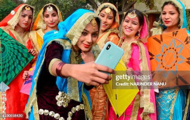 Students wearing traditional Punjabi outfits take selfies as they celebrate Lohri, the spring festival, in Amritsar on January 13, 2021.