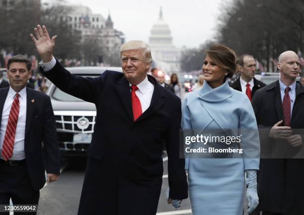 President Donald Trump waves while walking with U.S. First Lady Melania Trump, during a parade following the 58th presidential inauguration in...