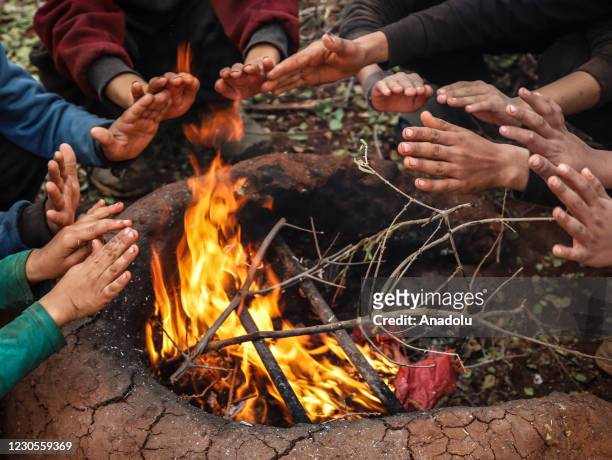 Kids are seen around a tent as Syrians set a fire in a tent by using dangerous materials to keep the family members warm due to cold winter...