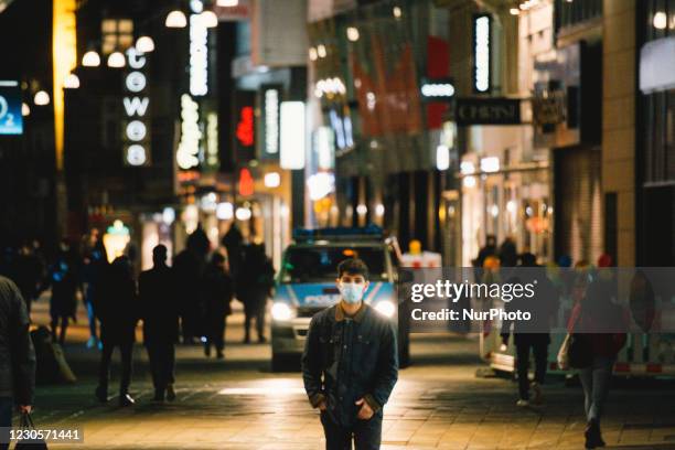 A man with face walk walks in the city center of Dortmund and police car are seen patrolling under the hard lock down imposed in Germany on January...