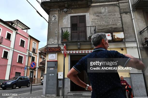 Man stand in front of a house of the fascist era, with writings and drawings depicting late Italian fascist leader Benito Mussolini, in the street of...
