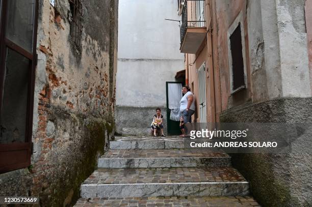 People stand in front of their house in a street of the old center in the town of Cinquefrondi in Calabria region in southern Italy, on July 6, 2020....