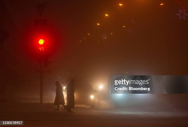 Pedestrians cross a street in near-darkness in Norilsk, Russia, on Monday, Dec. 21, 2020. Norilsk may soon be famous for a different type of mining...
