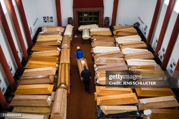 Employees store coffins, some marked with "infection risk" as others have "corona" scrawled in chalk, in the mourning hall of the crematorium in...