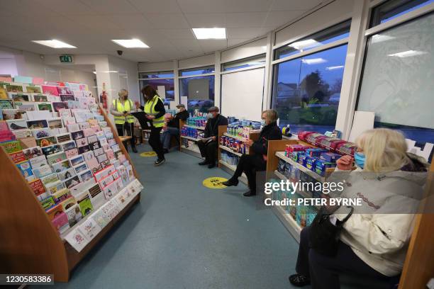 Patients wait in a socially-distanced queue ahead of receiving an injection of the coronavirus Covid-19 vaccine at Andrews Pharmacy in Macclesfield,...