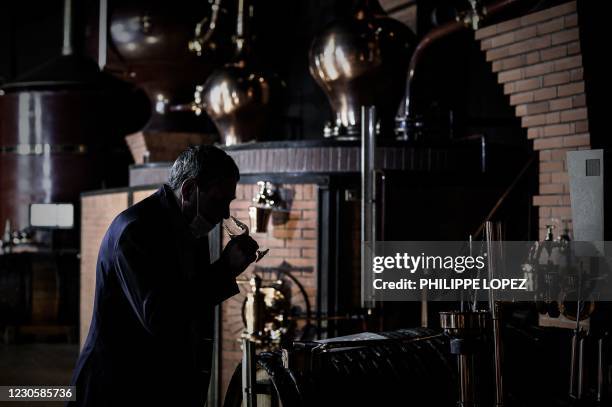 Distillery owner Eric Pinard checks the distillation process of Cognac, a white wine eau-de-vie obtained from a double distillation in a Charentais...