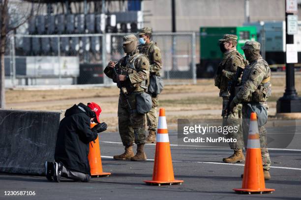 President Donald Trump supporter wearing a MAGA hat is seen praying in front o Members of The National Guard outside The US Congress. Washington,...