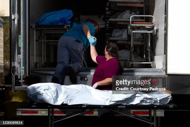 Employees prepare to move a body into a refrigerated semi-truck at the Pima County Office of the Medical Examiner on January 14, 2021 in Tucson,...