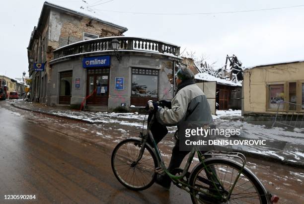 Woman pushes her bicycle along a street in the town of Petrinja on January 12 that was struck by a deadly earthquake on December 29. - Winter shows...