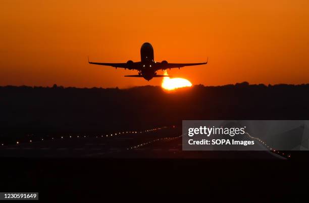 Plane seen taking off during sunset at Krakow's Balice airport.