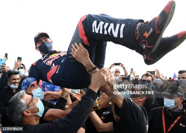 Mini's driver Stephane Peterhansel celebrates with teammates their victory after winning the Dakar Rally 2021, at the end of the last stage between...