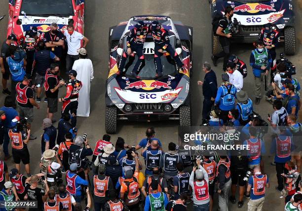 Mini's driver Stephane Peterhansel and his co-driver Edouard Boulanger of France celebrate their victory after winning the Dakar Rally 2021, at the...