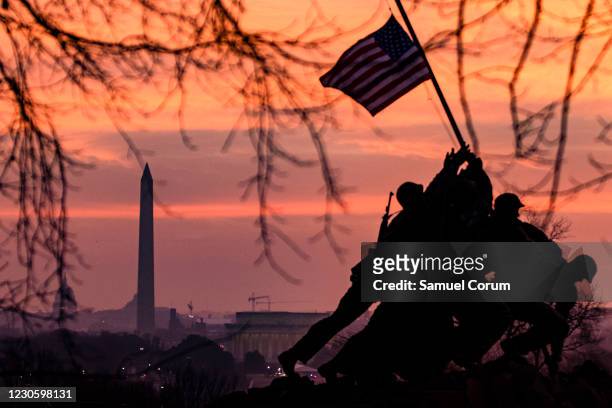 The American flag flies above the US Marine Corps War Memorial, also known as the Iwo Jima Memorial, with the Washington Monument in the distance on...
