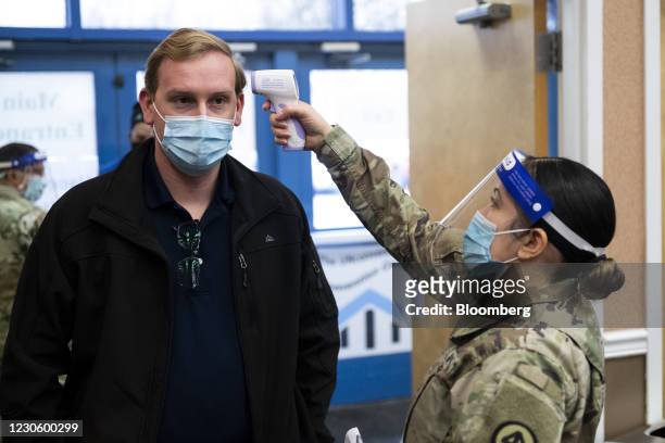 Person gets his temperature taken by a member of the National Guard before receiving a dose of a Covid-19 vaccination at the New Jersey Convention...