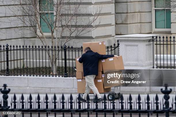 Man pushes a large cart full of boxes along West Executive Avenue between the West Wing of the White House and the Eisenhower Executive Office...