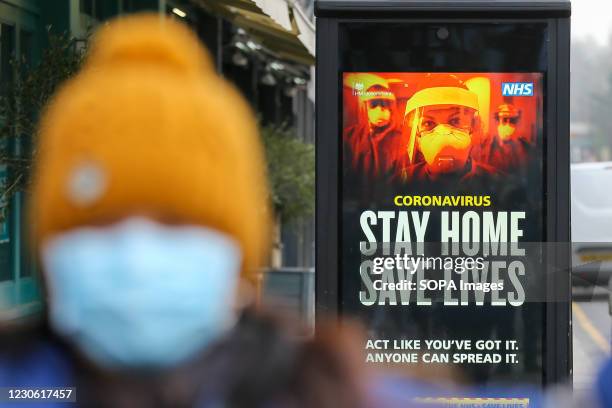 Woman walks past the Government's 'Stay Home, Save Lives' Covid-19 publicity campaign poster in London, as the number of cases of the mutated variant...