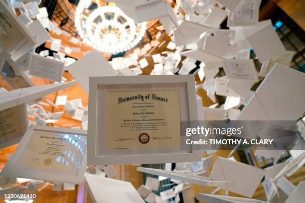 Diplomas are part of artwork, entitled "Da Vinci of Debt," on display at Grand Central Terminal on January 16 in New York. - The artwork is made up...