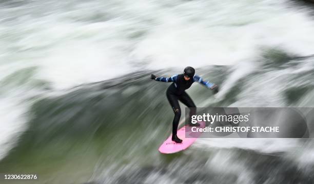 Picture taken with long time exposure shows a surfer riding on an artificial wave in the canal of the Eisbach river at the English Garden park in...