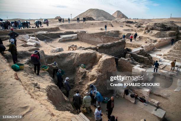 Workers excavate a site during the official announcement of the discovery by an Egyptian archaeological mission of a new trove of treasures at...