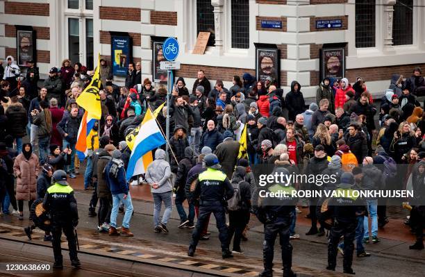 Dutch riot police stand near anti-government activists as they to denounce ongoing restrictions related to the coronavirus disease pandemic among...