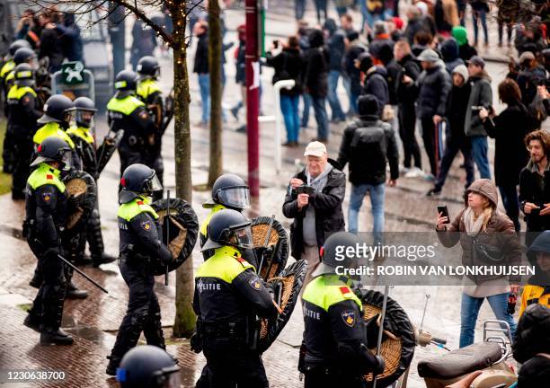 Dutch riot police stand near anti-government activists as they to denounce ongoing restrictions related to the coronavirus disease pandemic among...
