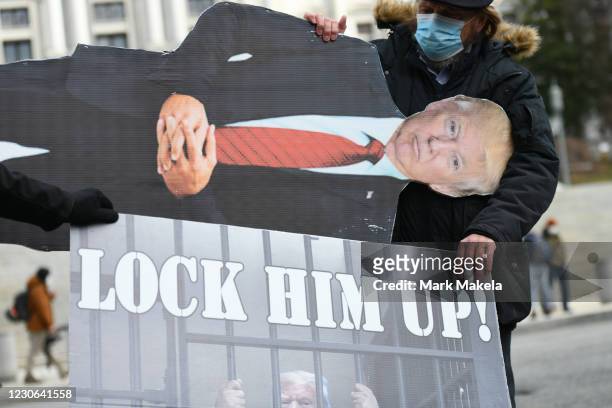 An effigy of President Donald Trump is lowered while people demonstrate against the president outside the Pennsylvania Capitol Building on January...