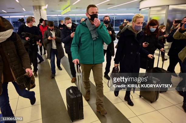 Russian opposition leader Alexei Navalny and his wife Yulia walk towards the passport control point at Moscow's Sheremetyevo airport upon the arrival...
