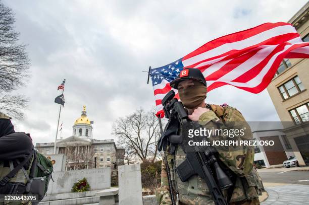 Armed members of the Boogaloo militia stand holding a flag in front of the State Capital in Concord, New Hampshire on January 17 during a nationwide...