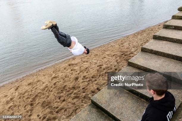 Young man is seen training parkour on Sunday sunny afternoon in Southbank embankment by the Thames River with the City in the background as the UK's...