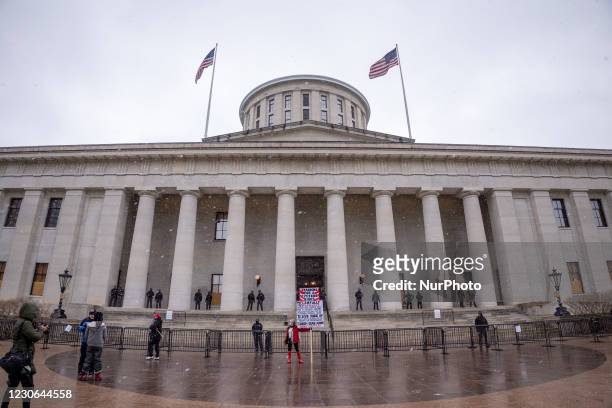 Trump supporter holds up a sign during an armed protest at the Ohio Statehouse ahead of the inauguration of President-elect Joe Biden in the wake of...