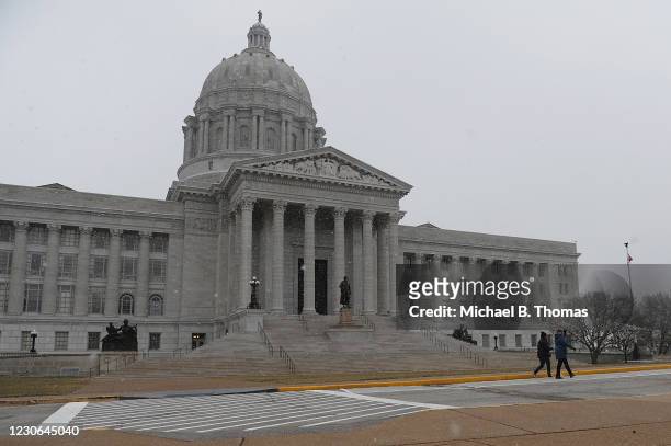 Pedestrians walk along as snow flurries fall outside the Missouri State Capitol Building on January 17, 2021 in Jefferson City, Missouri. Supporters...
